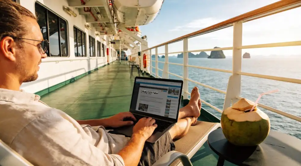 A laptop and a cold coconut sit on as small table