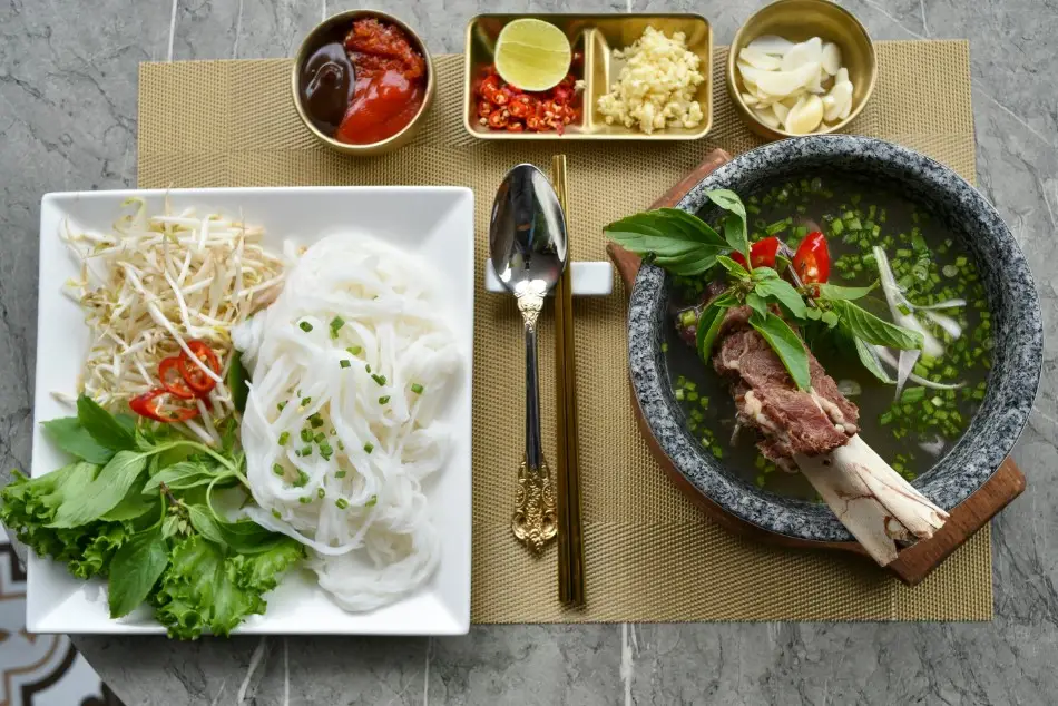 A vibrant layout of Vietnamese pho with fresh herbs noodles and condiments