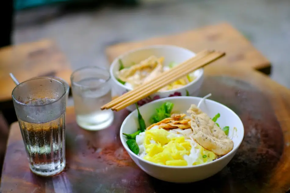Enjoy vibrant Vietnamese noodle bowls with fresh greens in Hue, Vietnam.