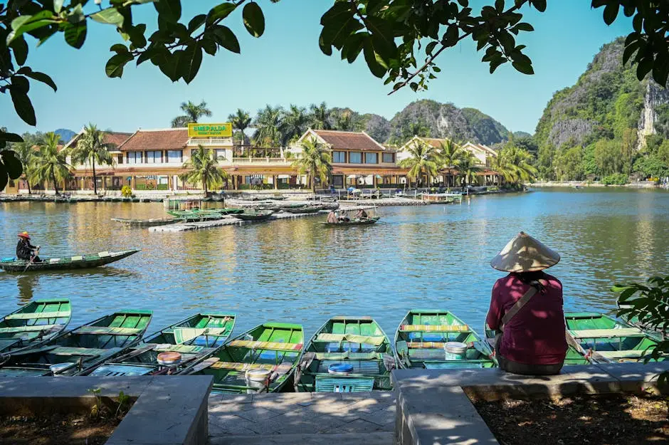 A Tranquil Riverside Scene With Traditional Asian Boats And A Person I