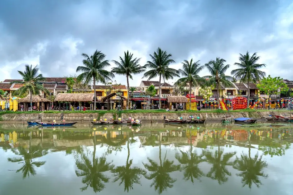Scenic Riverside View With Palm Trees And Boats In A Tropical Setting